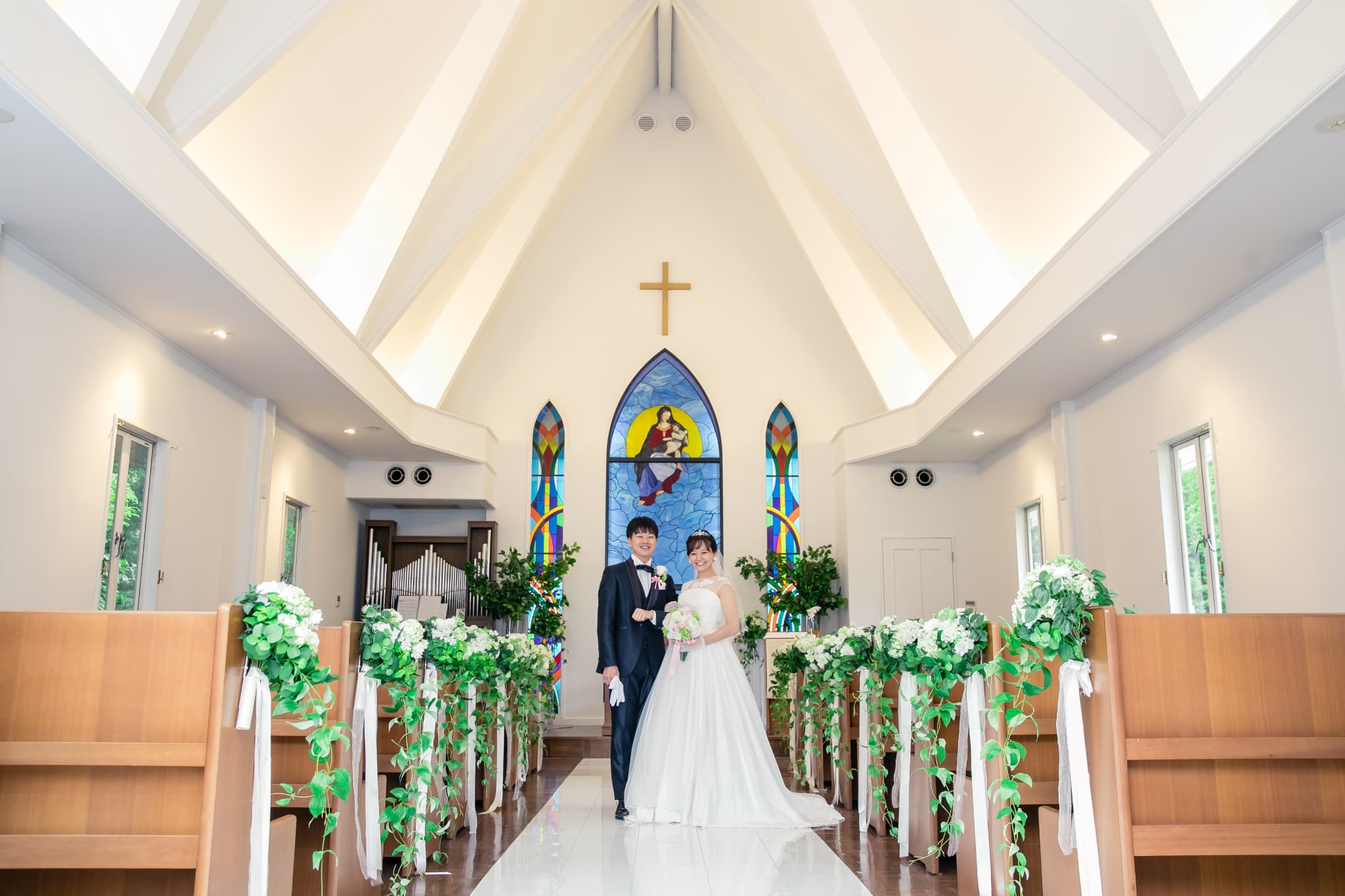 緑豊かなガーデンに佇む、白を基調とした「軽井沢アンジェロ教会」。祭壇には聖母マリアのステンドグラスが配され、おふたりの挙式を見守ります。